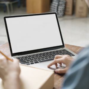 Online small business owner writing address on parcel box.
