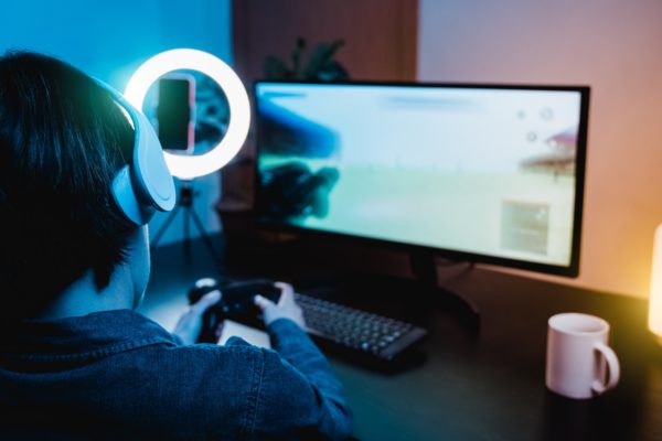 Young girl gamer playing and streaming video shooting game online